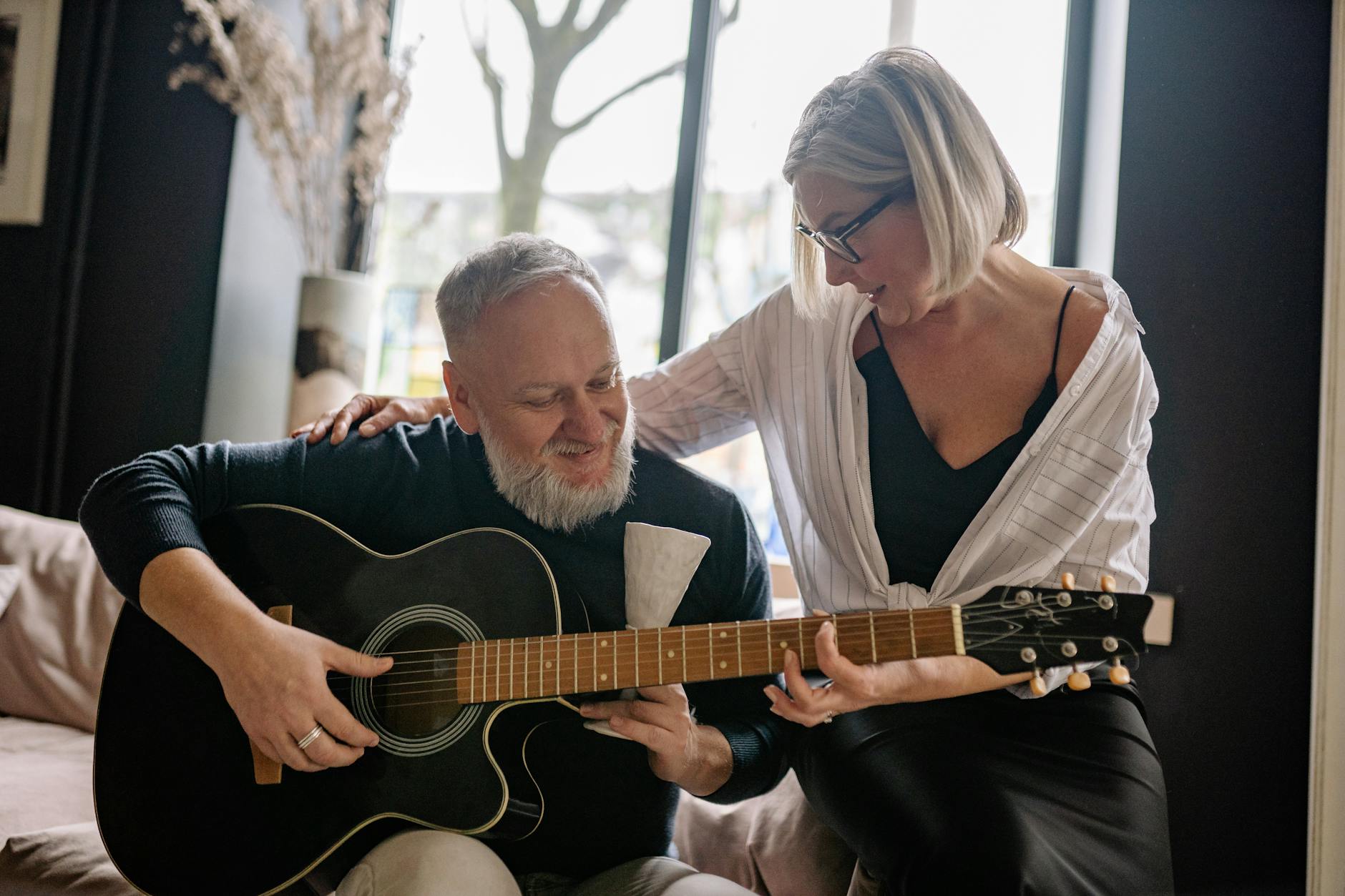 an elderly couple playing the guitar together